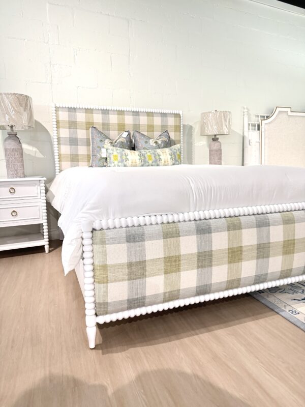 Queen spool bed in a white wooden finish with green blue and neutral gingham upholstered fabric, headboard, and footboard