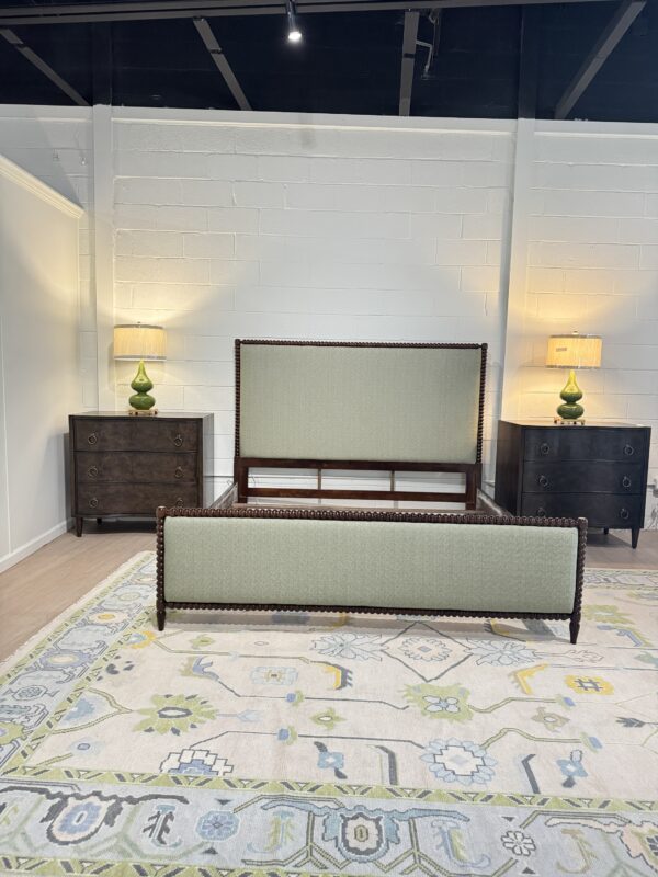 King spool bed in a tkb wooden finish with green  upholstered fabric, headboard, and footboard