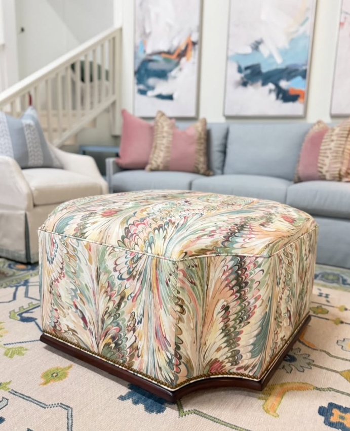 Furrow ottoman covered in aray multi with a wooden base and gold nail heads