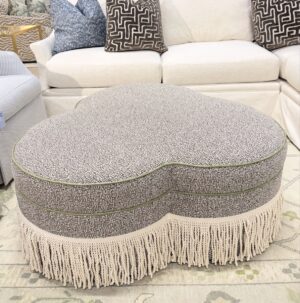 Upholstered, clover, ottoman in Laguana pebble with a green leather welt and bouillon fringe! This is spot clean